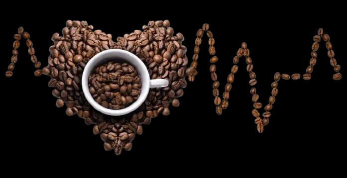 Granos de café formando un corazón alrededor de una taza